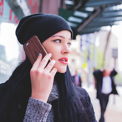 woman with dark hair wearing a beanie and talking on a phone