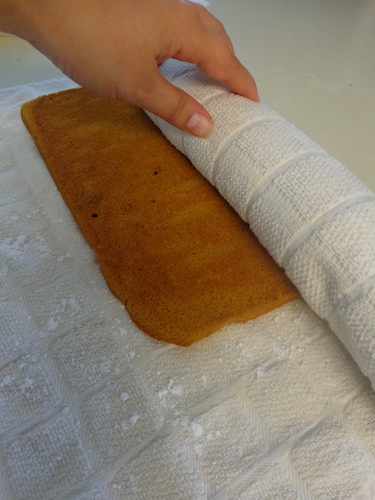 pumpkin roll being rolled in a dish towel