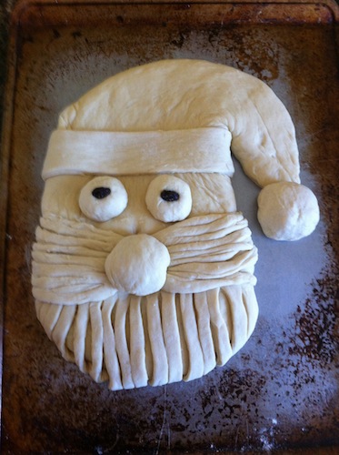 dough shaped as santa bread with raisins for eyes 