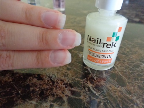 finger nails with polish beside a bottle of nail tek foundation III