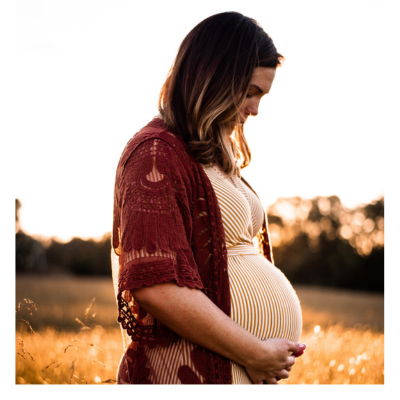 pregnant woman standing in a wheat field