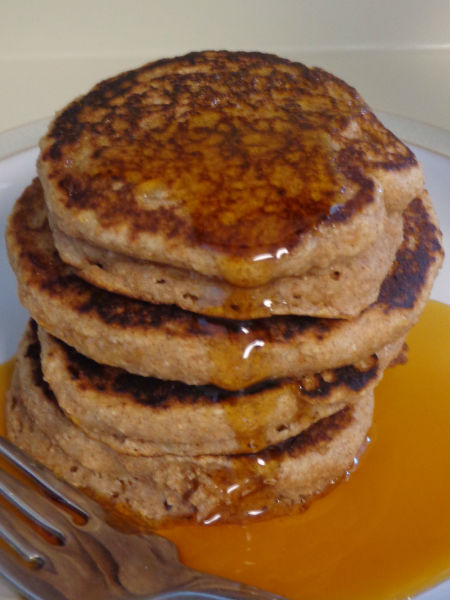 stack of cinnamon applesauce pancakes being drizzled with maple syrup
