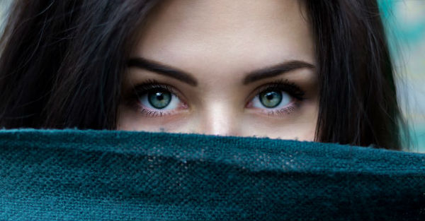 woman with piercing eyes looking over a piece of fabric