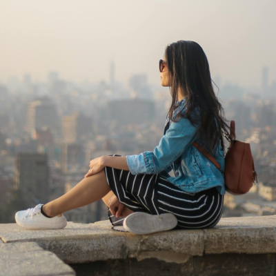 woman sitting on a ledge overlooking the city