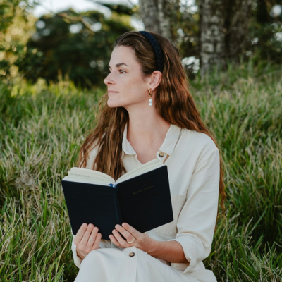 woman sitting on a grassy hill holding a bible