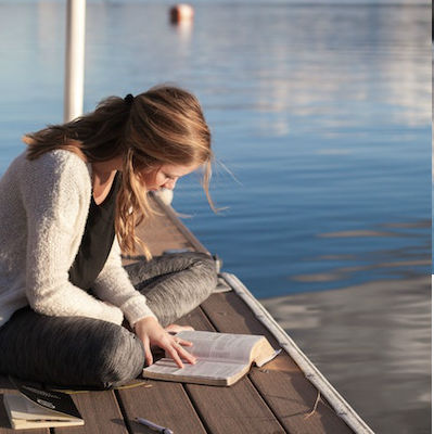 woman sitting on dock reading