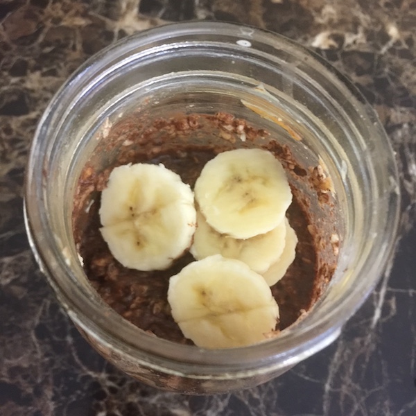 mason jar of chocolate peanut butter overnight oats topped with sliced banana