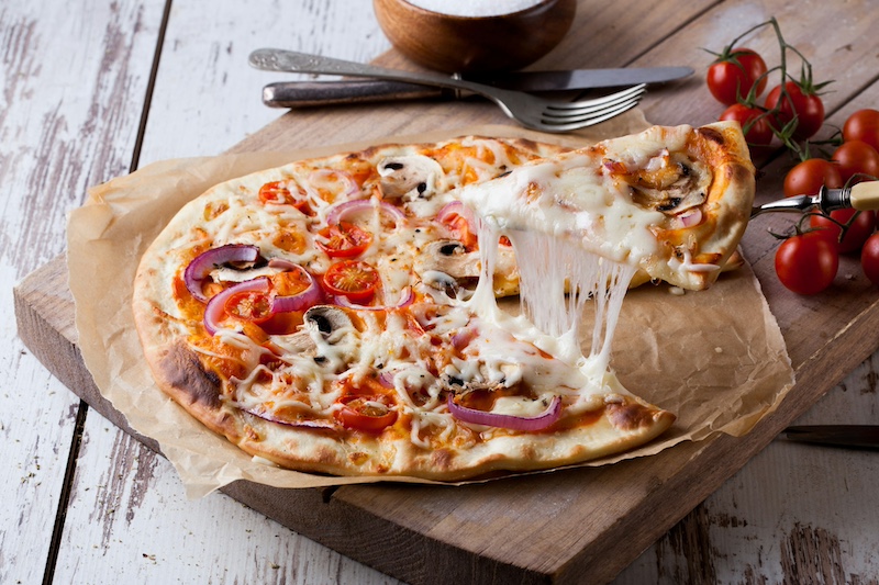 cheesy pizza on a brown wooden tray - choose easy meals to make hosting as an introvert less stressful 