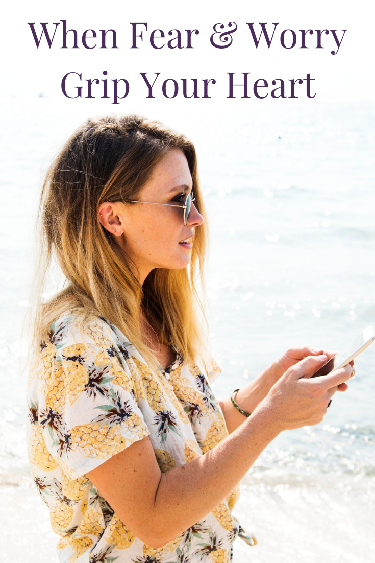 woman at ocean holding cell phone