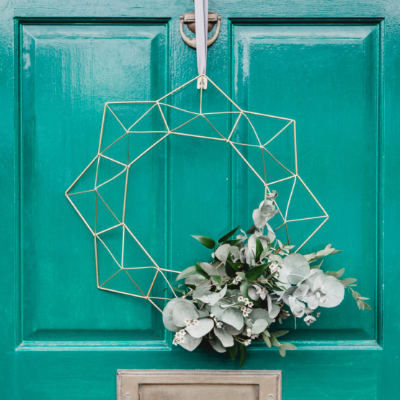 teal front door with silver wired and white flowered wreath