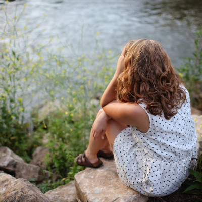woman sitting alone by the lake