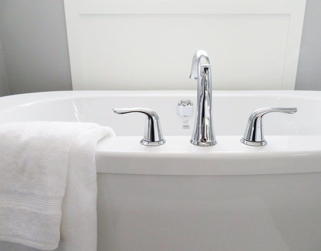 white bathtub with towel hanging over the side