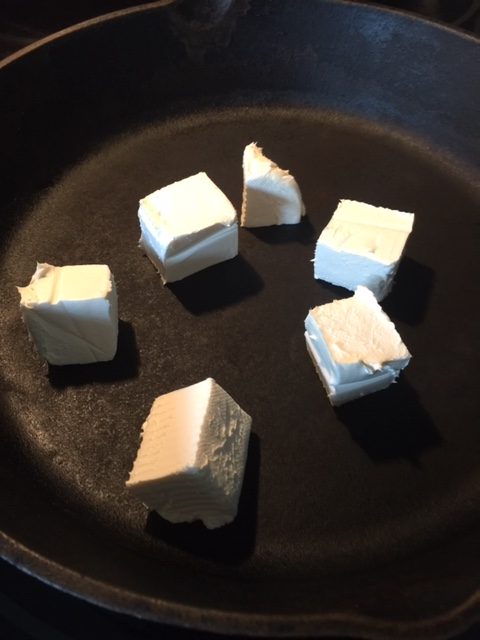 cubes of cream cheese in cast iron skillet