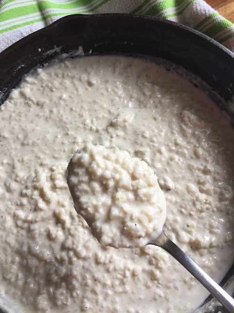 spoon full of riced cauliflower risotto over cast iron skillet