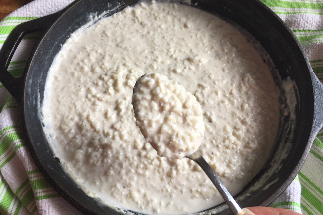 spoon full of riced cauliflower risotto over top of cast iron skillet