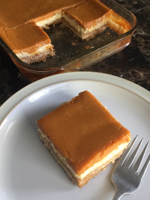 pumpkin cheesecake bar on plate beside pan