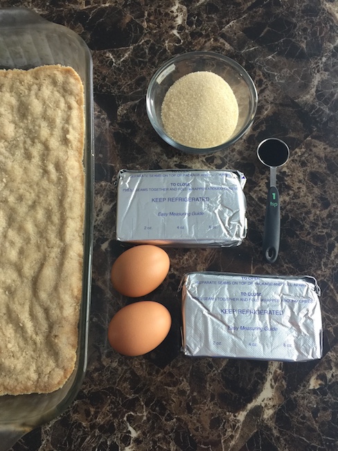 sugar, cream cheese, eggs beside cake mixture in pan