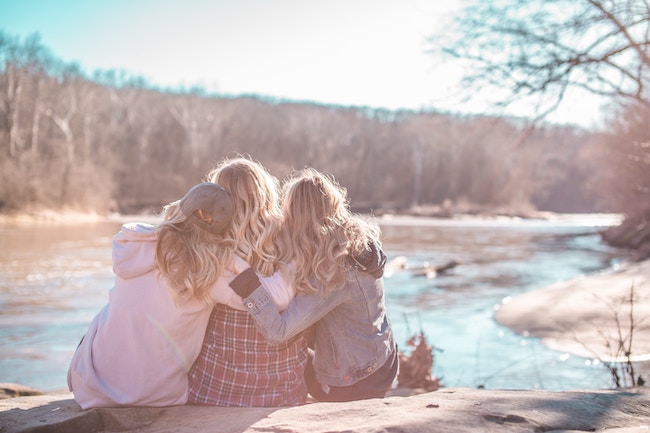 three woman sitting on rock