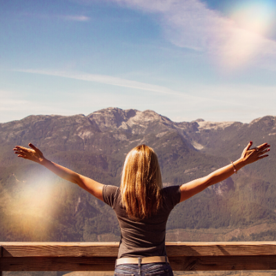 woman with outstretched arms looking at mountains