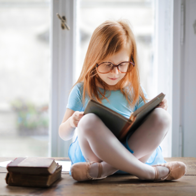 little girl with glasses reading a book