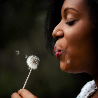 black woman blowing dandelion featured