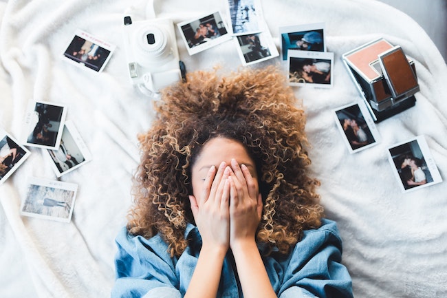 woman lying on bed surrounded by pictures