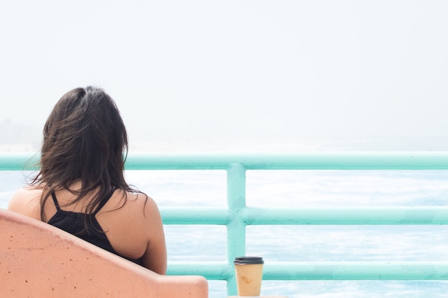 woman sitting on a bench looking at the ocean