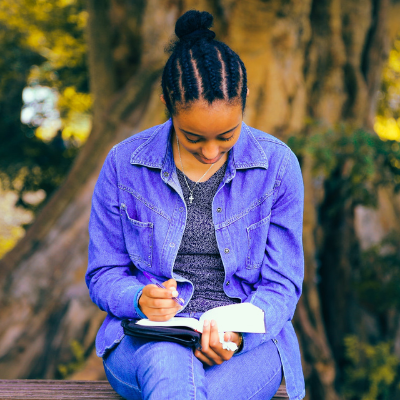 black woman sitting outside reading a book