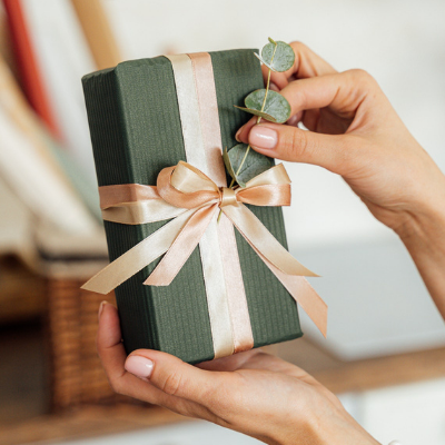 hand holding a green gift box with peach ribbon