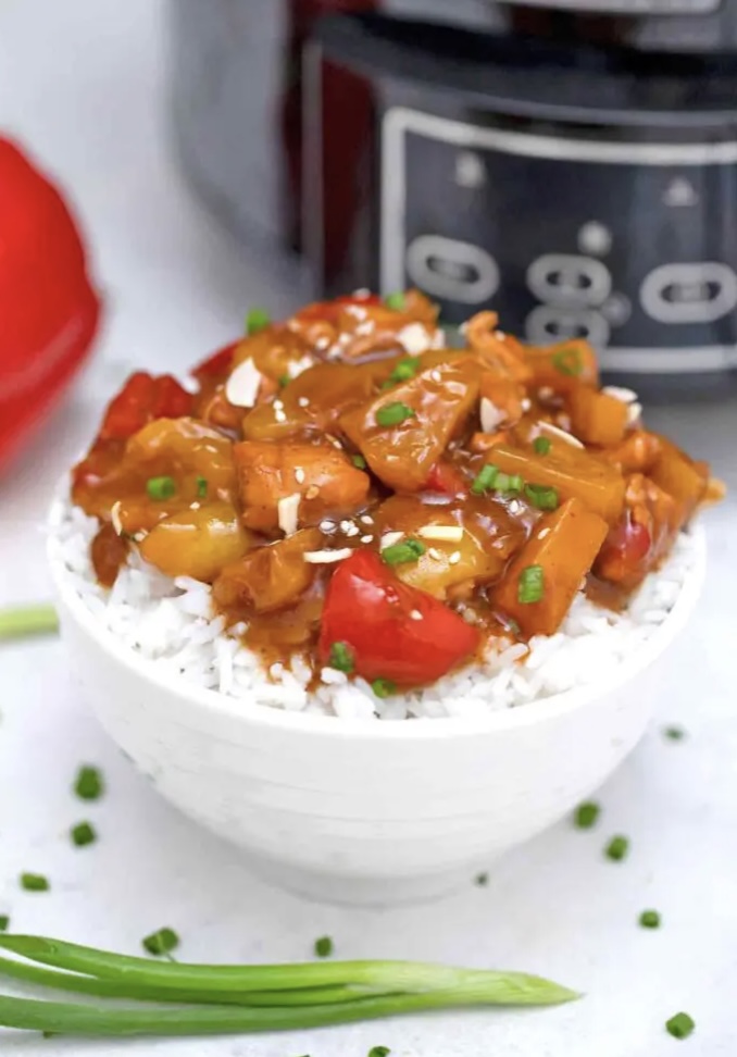 bowl of rice topped with glazed chicken and red pepper