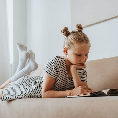 little girl lying on a couch reading