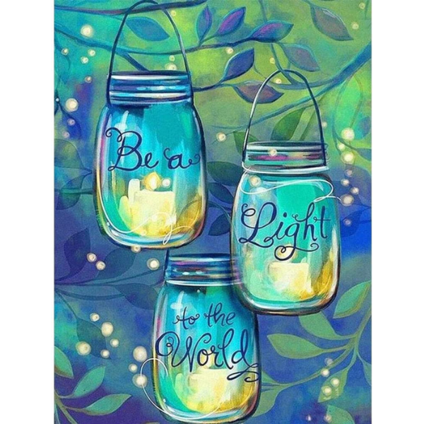 three mason jars with candles inside hanging from a tree