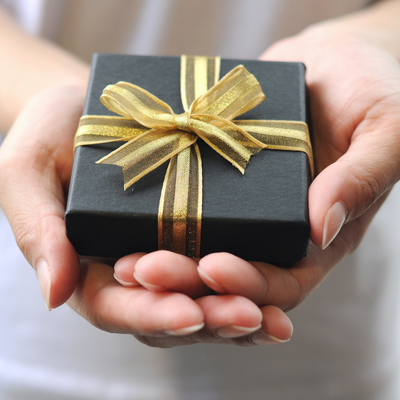 hand holding small black box with gold ribbon