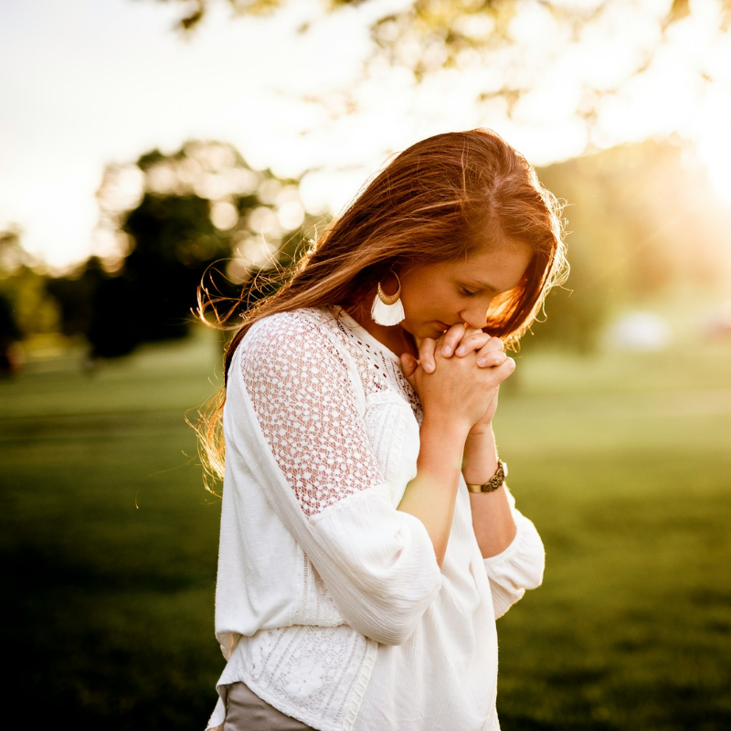 beginner's guide to learn how to pray - woman praying outside in grassy area