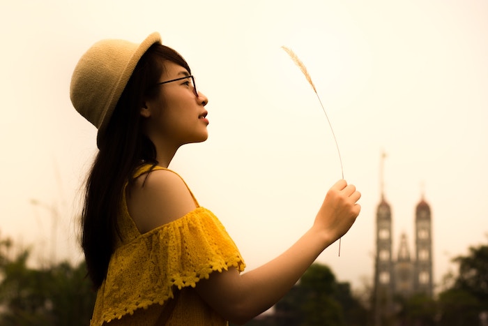 asian woman holding a piece of white grass