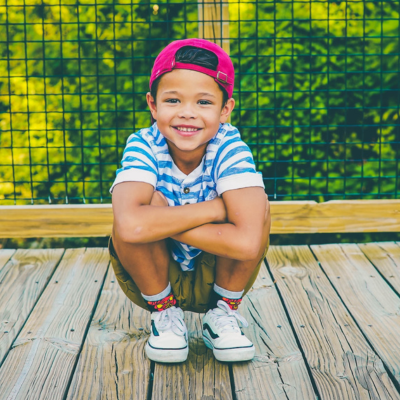 smiling little boy crouched down on a wooden deck