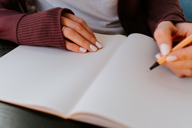 closeup of woman's hands writing in a journal