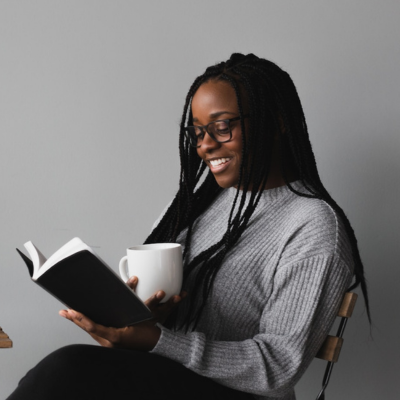 black woman sitting and reading a bible while holding a cup