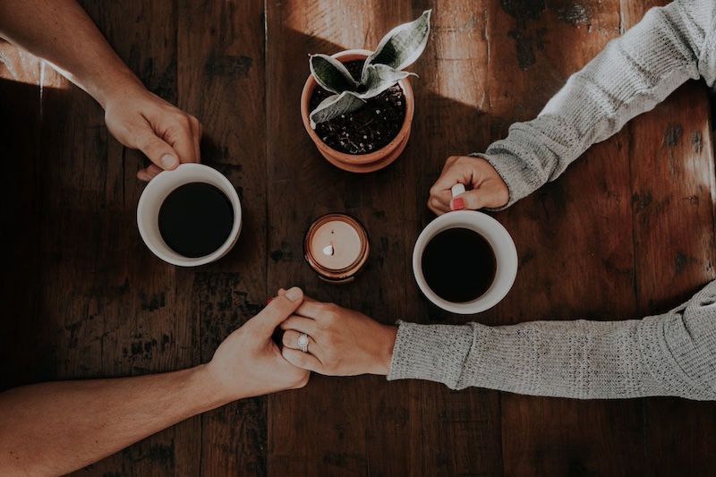 couple holding hands and white ceramic mugs