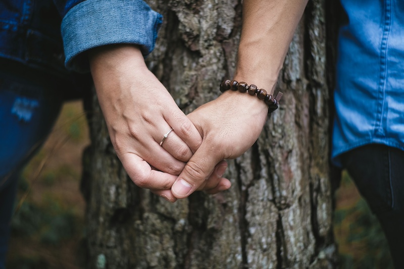 couple holding hands by a tree