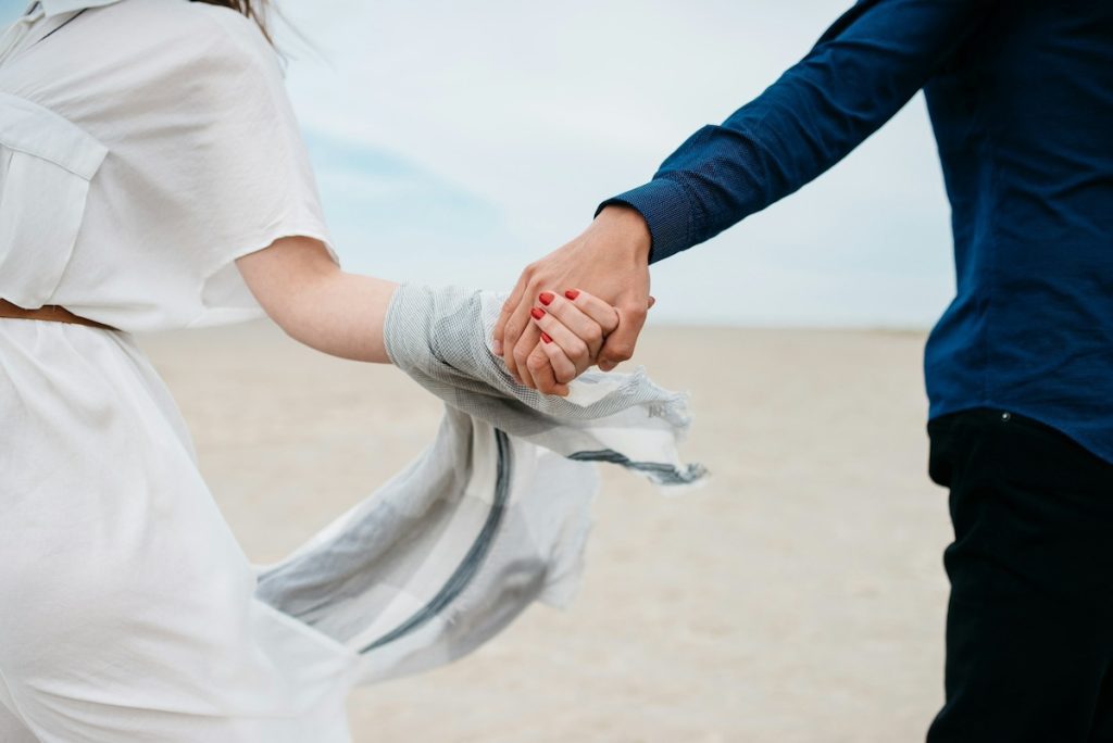 couple on a beach holding hands on a windy day