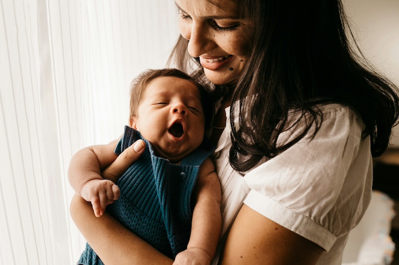smiling mom holding yawning baby