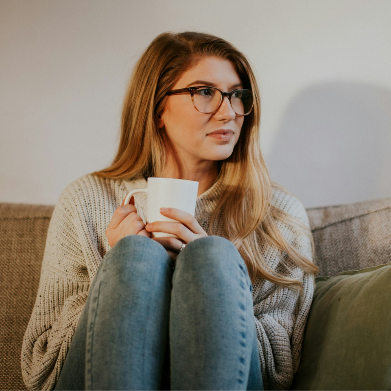 woman sitting on couch holding a coffee cup