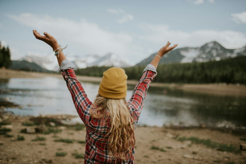 woman standing in front of a lake with her outstretched arms