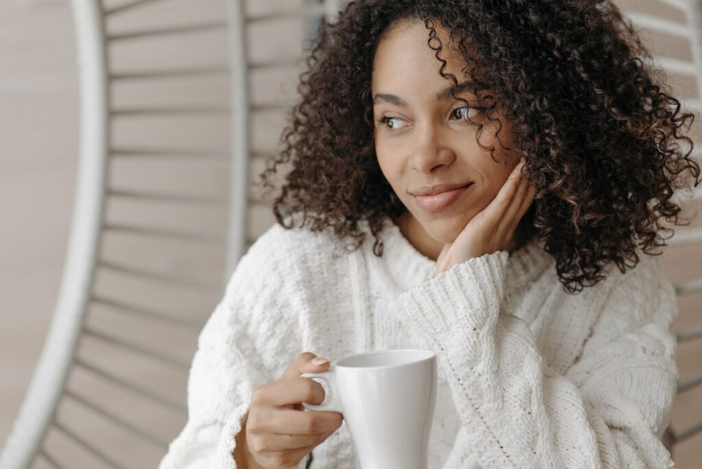 Woman holding a coffee mug and looking thoughtfully out a window