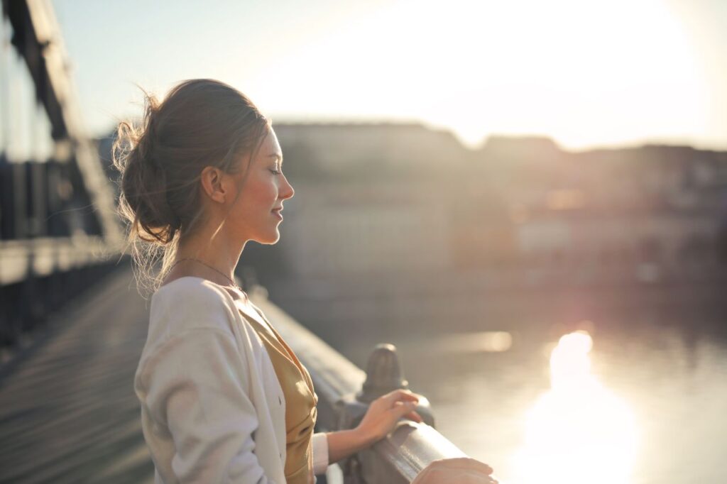 Woman standing peacefully by the water in warm sunlight